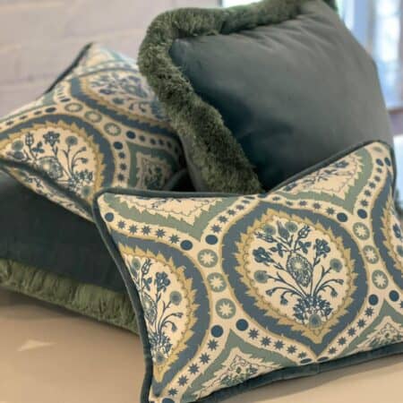 2 patterned white and blue cushions amongst of 2 blue cushions with green trim