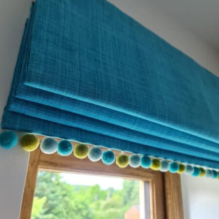 Blue blind with green and blue pom pom edging
