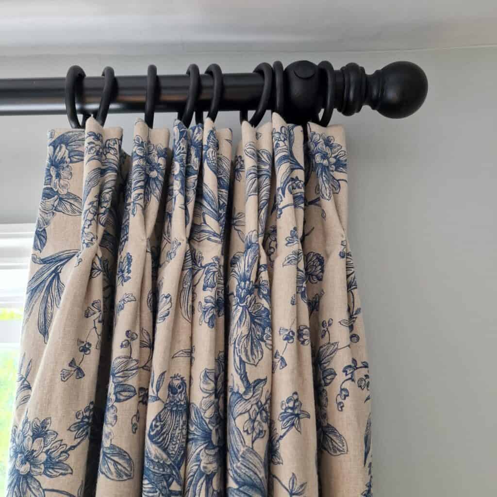 Cream curtains with blue detailing with black curtain pole