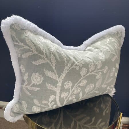 Grey and white cushion with white trim with floral embroidery
