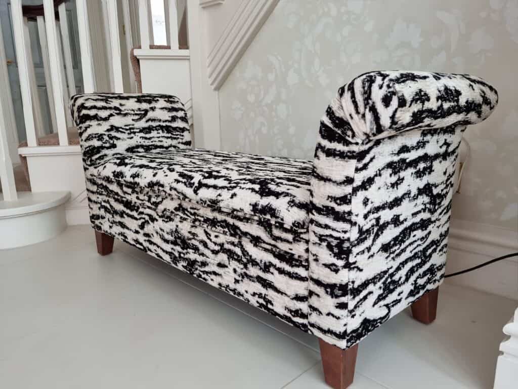 white and black pattered window seat with dark wood legs