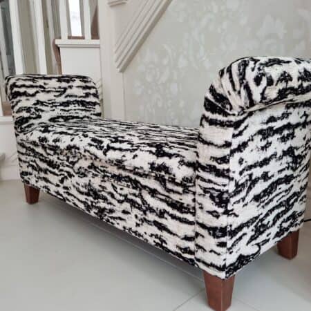 white and black pattered window seat with dark wood legs